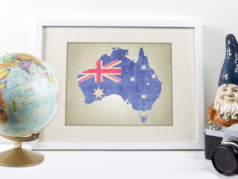 May include: A framed print of a map of Australia with the Australian flag superimposed on it. The map is printed on a textured paper with a vintage look. The frame is white with a white mat.