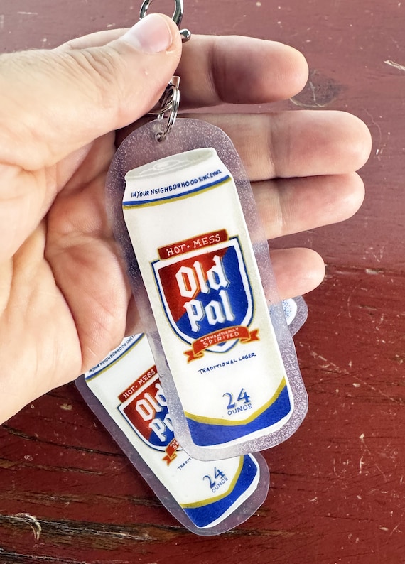 A miniature beer can immortalized in glossy resin as a keychain — tiny, tactile, and surprisingly convincing as a novelty everyday carry.