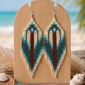 May include: A pair of long, diamond-shaped dangle earrings crafted from small beads in cream, dark green, brown, and bright blue. The earrings feature a geometric pattern with a central vertical brown stripe and fringe-like beaded strands.