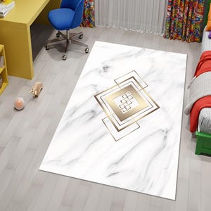 May include: A rectangular rug with a white marble pattern and gold geometric design. The rug features a central square with a smaller square inside, surrounded by a larger square frame. The rug is on a light grey wooden floor.
