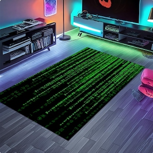 Op de afbeelding: Een rechthoekig zwart tapijt met een groen digitaal regenpatroon, dat doet denken aan computercode. Het tapijt ligt op een houten vloer en de kamer wordt verlicht met kleurrijke omgevingsverlichting.