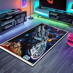 Könnte beinhalten: Rechteckiger Star Wars-Teppich mit dem Raumschiff Millennium Falcon in einer Weltraumszene mit anderen Raumschiffen und Explosionen. Der Teppich hat einen schwarzen Rand und das Star Wars-Logo.