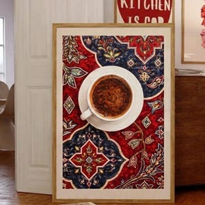 Könnte beinhalten: Ein gerahmter Druck mit einer Tasse Kaffee auf einer weißen Untertasse, vor einem rot-blauen Hintergrundmuster. Das Kunstwerk befindet sich in einem Holzrahmen und lehnt an einer weißen Tür. Über dem Rahmen befindet sich ein rotes herzförmiges Schild mit der Aufschrift "THIS KITCHEN IS CAD".