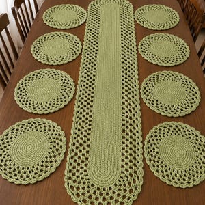 May include: A sage green crochet table runner with a solid centre and an openwork lace border, accompanied by eight matching round crochet placemats. Each piece features a consistent circular stitch pattern and a scalloped edge design.