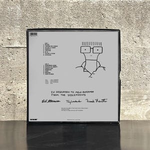 May include: A black and white album cover featuring a cartoon drawing of a person with glasses. The album cover includes a tracklist and the text "IN DEDICATION TO MILO AUKERMAN FROM THE DESCENDENTS."