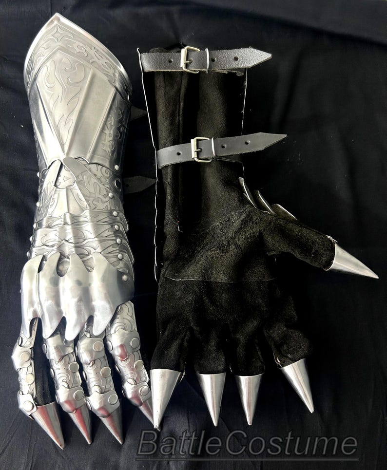 May include: A pair of medieval-style gauntlets. One is silver metal with ornate detailing, the other is black with silver claw-like tips. The black gauntlet has leather straps with buckles. The image includes the text "Battle Costume".