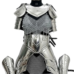 Puede incluir: Un traje de batalla completo de color plateado, que incluye una coraza, protectores de hombros y protectores de brazos. La pieza del pecho presenta cota de malla y detalles met&aacute;licos decorativos. El texto "Battle Costume" es visible en la parte superior.