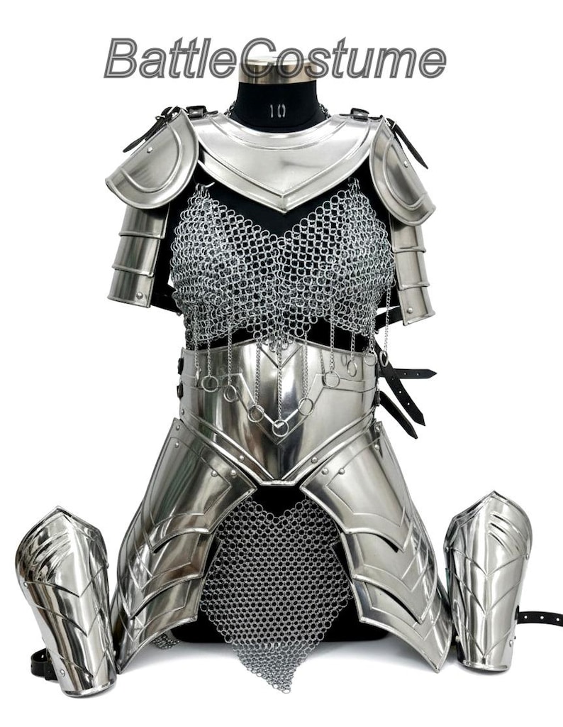 Puede incluir: Un traje de batalla completo de color plateado, que incluye una coraza, protectores de hombros y protectores de brazos. La pieza del pecho presenta cota de malla y detalles met&aacute;licos decorativos. El texto "Battle Costume" es visible en la parte superior.