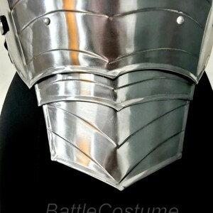 May include: Close-up of a polished, silver chest armour piece. The armour has a layered design with riveted details and a reflective surface. The text "BattleCostume" is visible at the bottom. This item is likely for cosplay or historical reenactment.