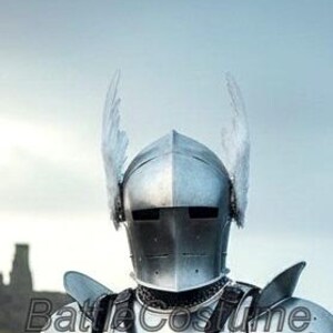 K&ouml;nnte beinhalten: Nahaufnahme eines silbernen Ritterhelms mit zwei gefiederten Verzierungen. Der Helm ist Teil einer R&uuml;stung, mit sichtbaren Schulter- und Brustplatten. Der Hintergrund zeigt eine verschwommene Landschaft und den Text "Battle Costume".