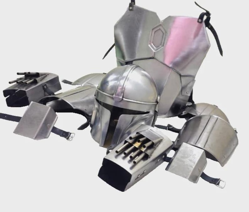 May include: A silver-colored Mandalorian armor set, including a helmet, chest plate, shoulder pads, and gauntlets. The armor has a metallic finish and is designed with detailed panels and straps. The helmet features a T-shaped visor.