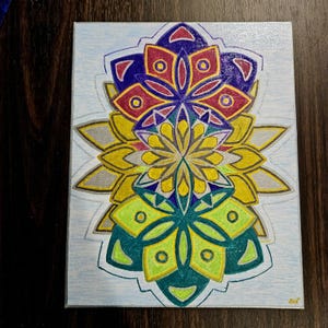 May include: A colorful abstract painting on canvas. The artwork features a symmetrical floral design with layers of blue, red, yellow, green, and silver. The painting is on a rectangular canvas.