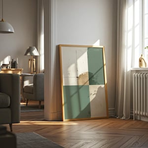 Könnte beinhalten: Ein gerahmtes abstraktes Kunstwerk mit einem goldenen Rahmen, das an einer Wand lehnt. Das Kunstwerk zeigt ein Raster aus weißen, grünen und beigen Quadraten. Der Raum hat Parkettböden und ein Fenster mit natürlichem Licht.