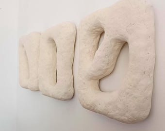 Può includere: Tre sculture da parete rettangolari color bianco sporco, testurizzate, con bordi irregolari e organici e grandi centri cavi. Ogni pezzo presenta una finitura superficiale ruvida e opaca e una struttura a telaio spessa e massiccia.