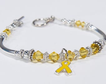 May include: A silver bangle bracelet with yellow crystal beads and a yellow ribbon charm.