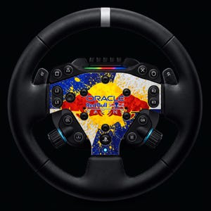 Puede incluir: Un volante de juego negro con una placa central que presenta un diseño de salpicaduras de pintura amarilla, azul y blanca. El logotipo de Oracle Red Bull Racing está impreso en el centro. El volante incluye varios botones, palancas y un logo de PlayStation.