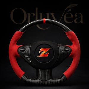 Könnte beinhalten: Ein schwarzes und rotes Lenkrad mit Carbonfaser-Finish. Das Lenkrad hat rote Wildledergriffe und einen roten Akzentstreifen oben. In der Mitte befindet sich ein schwarzes Emblem mit einem stilisierten roten und gelben "Z"-Logo.
