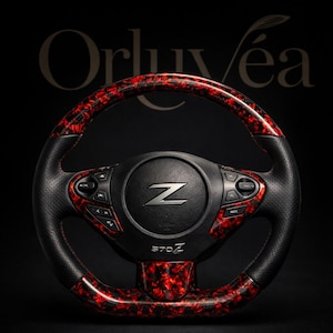 Puede incluir: Un volante de coche personalizado con un diseño negro y rojo. El volante presenta un centro negro con la letra "Z" y el texto "370Z". El borde tiene un patrón veteado rojo y negro.