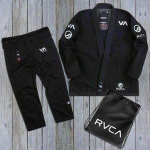May include: A black martial arts uniform set, comprising a jacket, trousers, and a drawstring bag. The jacket and trousers display the "RVCA" logo in white. The jacket has white detailing on the sleeves. The drawstring bag also features the "RVCA" logo.