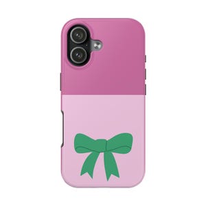 Peut inclure: Coque de téléphone bicolore rose et rose clair. La partie supérieure est rose uni, tandis que le bas présente un fond rose clair avec un motif de nœud vert. L'étui a une découpe pour l'appareil photo et des boutons latéraux.
