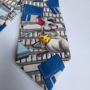 Könnte beinhalten: Eine Krawatte mit einem sich wiederholenden Muster aus Computertastaturen, Disketten und einer Cartoon-Maus, die ein Stück Käse hält. Die Krawatte hat ein hellblaues, graues und weißes Farbschema.