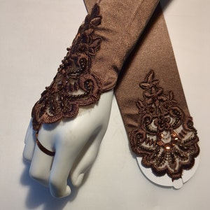 May include: A pair of brown satin elbow length gloves with lace and beaded embellishments.