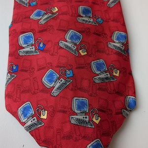 May include: A red silk tie with a repeating pattern of cartoon computers. The computers are gray with blue screens and have a yellow mouse and a red cord.