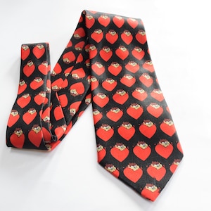 May include: A black silk tie with a red heart pattern featuring a cartoon character. The hearts are filled with a red color and the character is in a yellow and brown color.