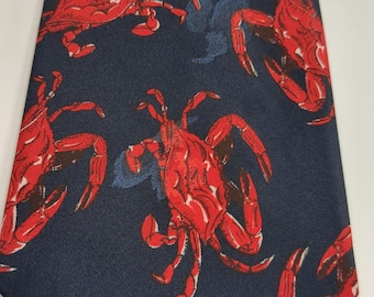 Puede incluir: Corbata azul marino con un patrón repetido de cangrejos rojos. Los cangrejos tienen pinzas y patas detalladas, sobre un fondo azul oscuro. Un accesorio clásico.