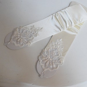 Guantes sin dedos de satén elástico con brillo fruncido color marfil, encaje con cuentas hasta el codo y presilla para el dedo