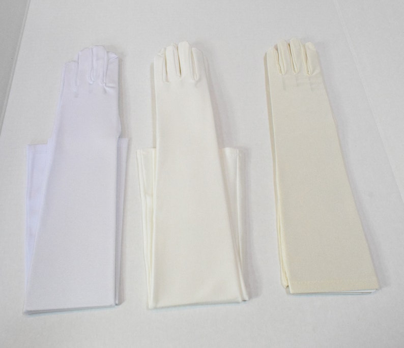 Puede incluir: Tres pares de guantes largos blancos, un par es marfil, un par es blanco y un par es de un tono blanco m&aacute;s claro.