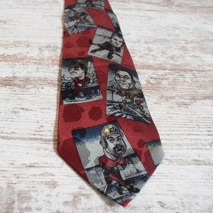 May include: Red silk tie with a repeating pattern of cartoon baseball players. The tie features a red background with white and gray details.