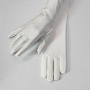 Puede incluir: Un par de guantes de sat&eacute;n blanco, un guante est&aacute; doblado sobre el otro, con las yemas de los dedos de ambos guantes visibles.