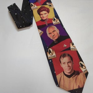 May include: A black necktie featuring a space-themed background with white stars and four rectangular panels displaying Star Trek characters. Each panel includes the Star Trek 30 Years logo. The characters are Benjamin Sisko, Kathryn Janeway, Jean-Luc Picard, and James T. Kirk.