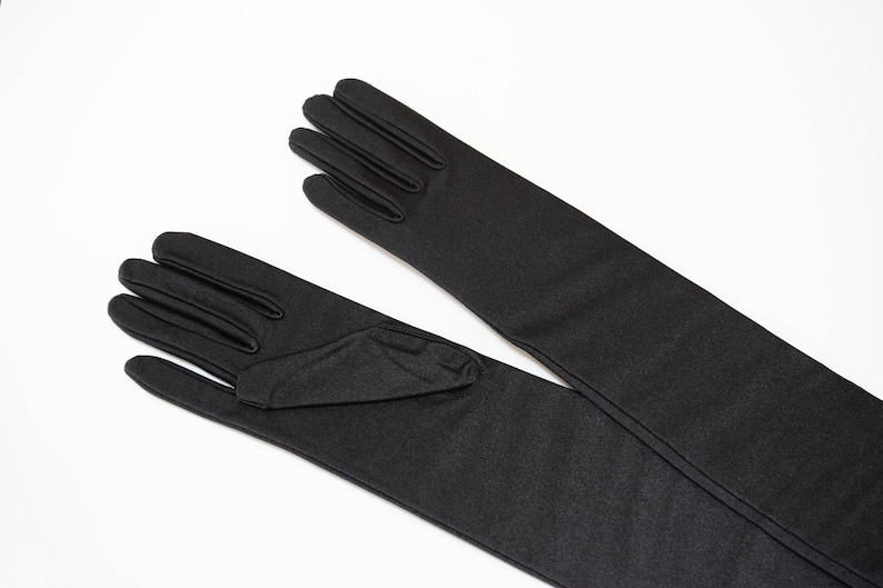 May include: A pair of long black gloves with a smooth, matt finish. The gloves are made of a stretchy fabric and have a close-fitting design.