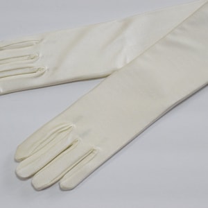 Puede incluir: Un par de guantes largos de sat&eacute;n blanco. Los guantes est&aacute;n completamente extendidos y los dedos est&aacute;n extendidos.