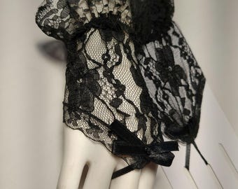 May include: Black lace wrist cuffs with a ruffled top and a black satin bow.