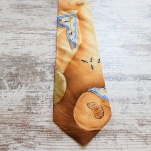 May include: A brown silk tie with a surrealist design featuring a clock face, a brown shape, and ants. The tie has a blue and white trim.