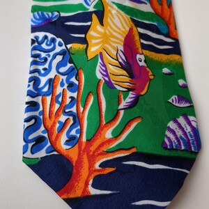 May include: A colorful silk tie with a tropical fish and coral reef pattern. The tie features a variety of fish, including a yellow and purple fish, a blue and white fish, and a red and orange fish. The background is a green and blue color.