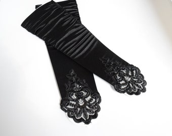 May include: A pair of black satin elbow-length gloves with black lace and bead embellishments at the cuffs.