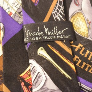 Puede incluir: Una corbata de seda negra con tem&aacute;tica de golf. La corbata presenta una variedad de palos de golf, pelotas de golf y las palabras "Top Flite" y "Elite". La corbata tambi&eacute;n tiene una etiqueta que dice "Nicole Miller" y "&copy; 1994 Nicole Miller".