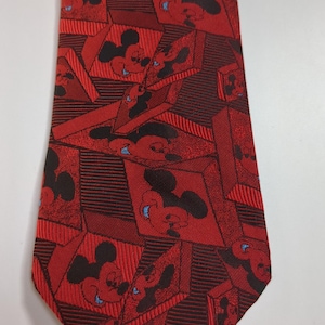 May include: A red silk tie with a repeating pattern of Mickey Mouse heads in black and white. The tie has a geometric design with red and black stripes.
