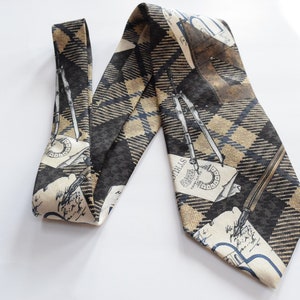 Puede incluir: Una corbata de patrón marrón y beige con un diseño de bolígrafos, compases y escritura sobre un fondo a cuadros.