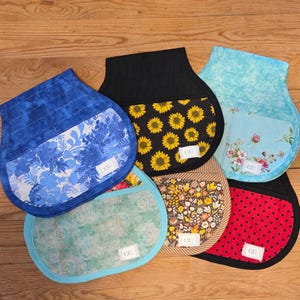 May include: Six fabric pocket organizers with rounded bottoms and top openings. Each features a unique pattern including blue floral, black sunflower, light blue floral, green swirl, brown botanical, and red with black polka dots, all with a small white tag.