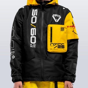 May include: Black and yellow jacket with a hood. The jacket features the text "50/60" in white on the front and a yellow pocket with the text "NYCC 25". The jacket has a zipper closure and multiple graphic designs.