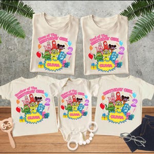 May include: Five cream-colored shirts and a bodysuit featuring a colorful graphic of cartoon monsters, balloons, and gifts. The text reads Mom, Dad, Brother, Sister, and Birthday Girl of the Birthday Girl, with the name Olivia and the number 2.
