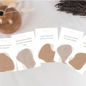 Op de afbeelding: Een verzameling witte kaarten met tekst en lijntekeningen van zwangere mensen. De kaarten hebben een neutraal kleurenpalet met bruine en beige accenten. De tekst bevat zinnen als "Ik ben klaar om het wonder van de geboorte te omarmen."