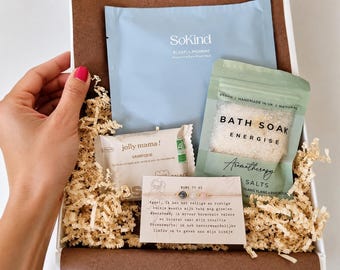 Può includere: Una scatola regalo contenente una maschera viso azzurra SoKind, una bustina verde di sali da bagno Energise, una piccola confezione di snack Jolly Mama e un biglietto Mama To Be con un delicato braccialetto di perline grigie e rosa.