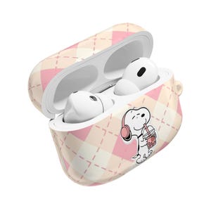 Op de afbeelding: Witte draadloze oortelefoons in een patroonhoesje. De hoes heeft een roze en crème ruitpatroon met een Snoopy-afbeelding die een drankje drinkt. De hoes is open en toont de oortelefoons binnenin.