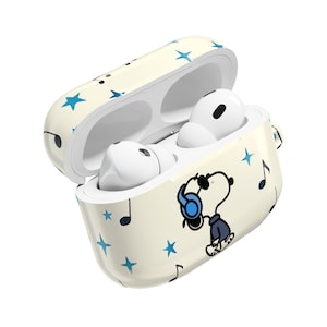 May include: Cream-colored AirPods case with a cartoon Snoopy graphic wearing headphones, surrounded by blue stars and musical notes. The case is open, revealing white earbuds inside. A fun and stylish accessory.